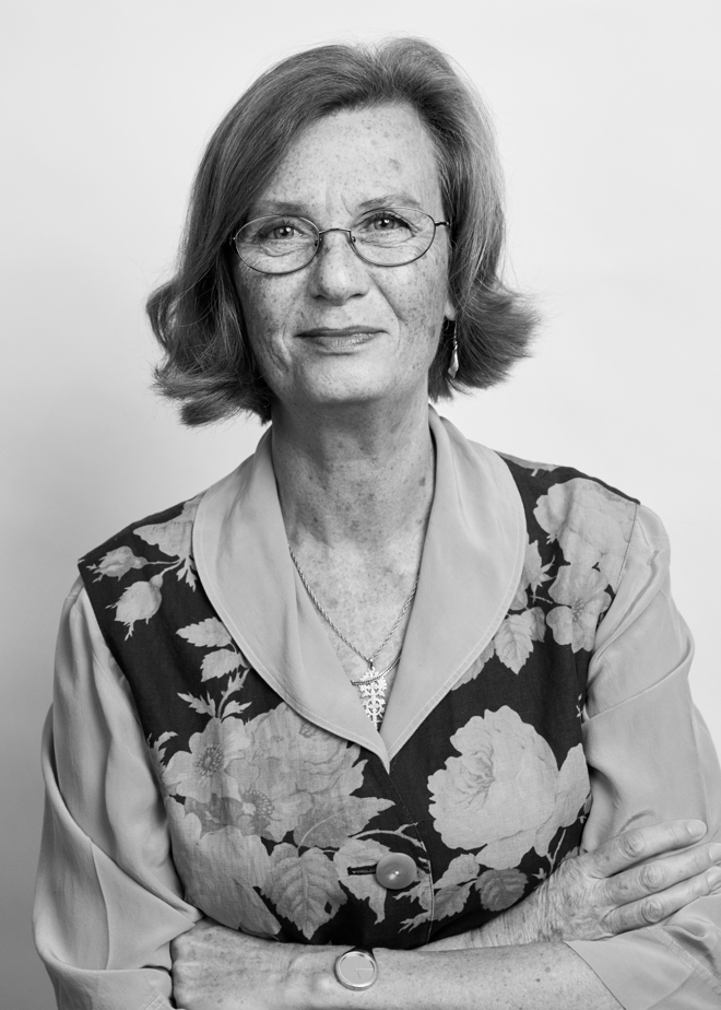 svartvitt porträtt på kvinna med glasögon, lockigt hår, mönstrad klänning