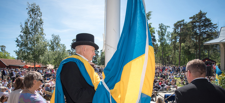 Flaggan hissas i samband med nationaldagsfirande på Torekällberget.