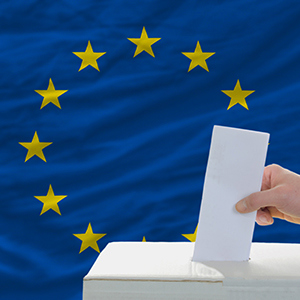 Bild på EU-flaggan och en hand som stoppar ner sin valsedel i en valurna.