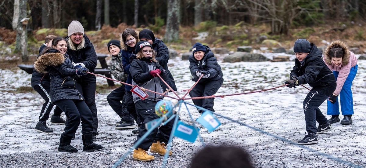 Fotografi på en dragkamp mellan en grupp skolelever i skogen.